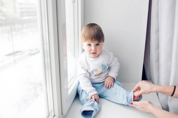 Adorable little baby seating on windowsill. look at the camera — Stock Photo, Image
