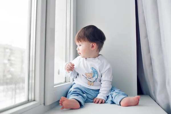 Pencere kenarında oturma sevimli küçük bebek. pencereden dışarı bakıp