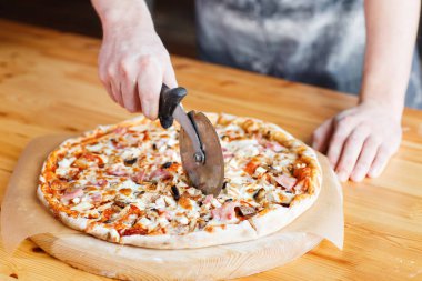 disk bıçak kesiyor. Ev yapımı Pizza jambon, mantar, mozzarellail. Şef önlük
