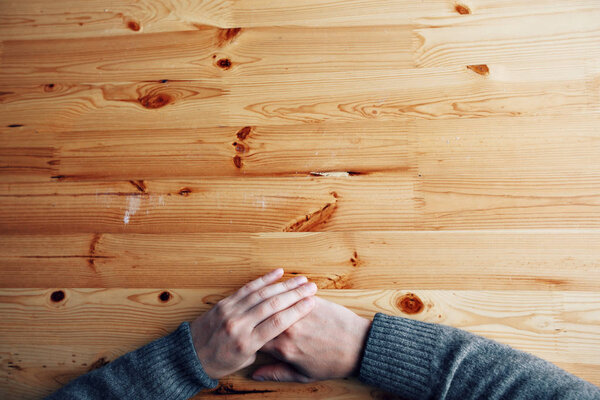 A men hands on a blank wood desk, top view at the studio.