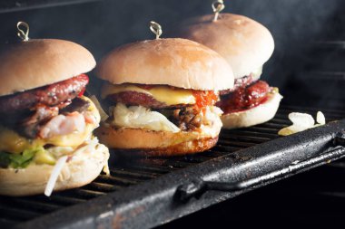 Sığır eti, domates, peynir ve marul ile lezzetli hamburger. Monte ızgarada pişirilir. ısı ızgara ve tüten dumanı.