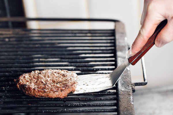 Beef Burger And Spatula On The Hot Flaming BBQ Charcoal Grill, Close-up