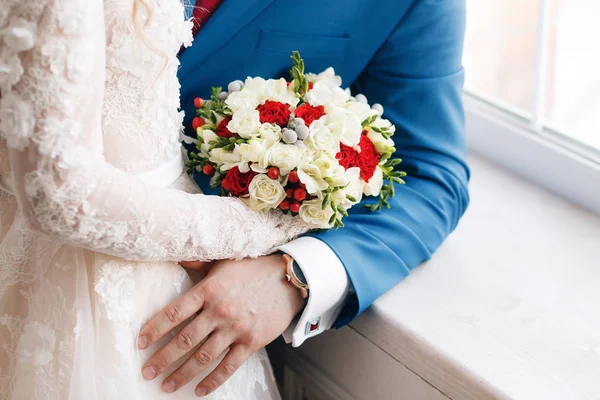 Nevěsta a ženich drží svatební kytice zblízka. červené a bílé růže, frézie, brunia zařízené ve složení — Stock fotografie