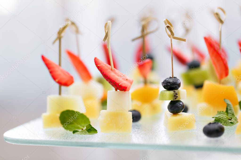 Appetizers, gourmet food - canape with cheese and strawberries, blue-berries catering service. selective focus, top view.