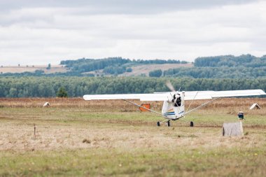 Küçük pervaneli uçak ile parlak doğal peyzaj çim kapalı alır. Arka plan üzerinde ağaçları vardır. Seçici odak uçakta. Kenarlıksız seyahat kavramı