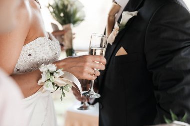 Mutlu yeni evli çift, beyaz İçecek şampanya şarap. Bir şekilde dekore edilmiş kristal gözlük. Gelin ve damat ile altın yüzük tost alkollü içecekler ile elleri. Yeni aile karı koca angajman kutlamak