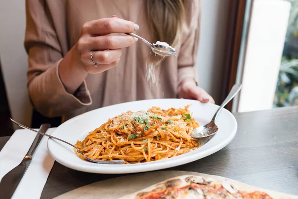 Girl eats Italian pasta with tomato, meat. Close-up spaghetti Bolognese wind it around a fork with a spoon. Parmesan cheese — Stock Photo, Image