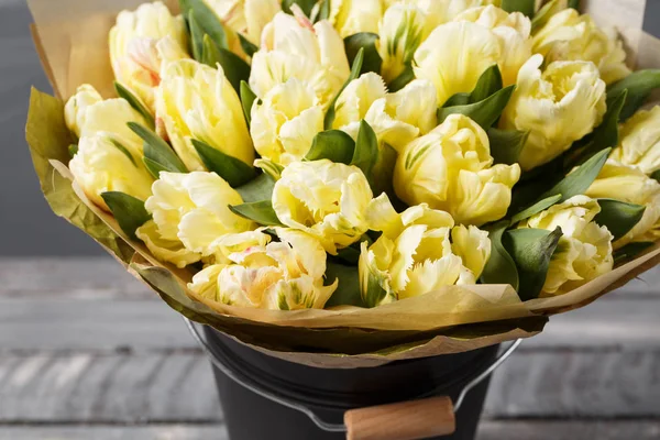 Tulipes de couleurs pastel jaune doux dans un vase sur une table en bois. Mur gris — Photo