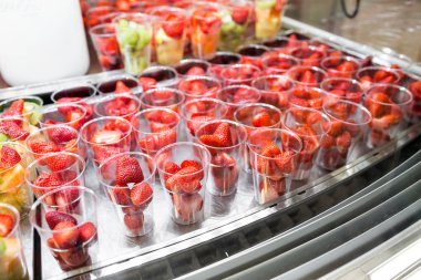 Satılık plastik bardak düzenlenmiş meyve salatası. buzdolabı vitrin veya açık büfe. Kokteyller ve çikolata çeşme için bir malzeme olarak kullanılır. Seçici odak