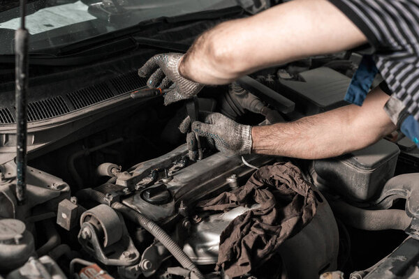 Замена свечей зажигания. механик в гараже. грязный реальный кадр
