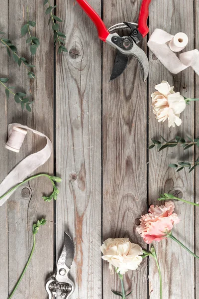Цветы и садовые инструменты. Рабочий стол флориста с аксессуарами серый деревянный фон . — стоковое фото