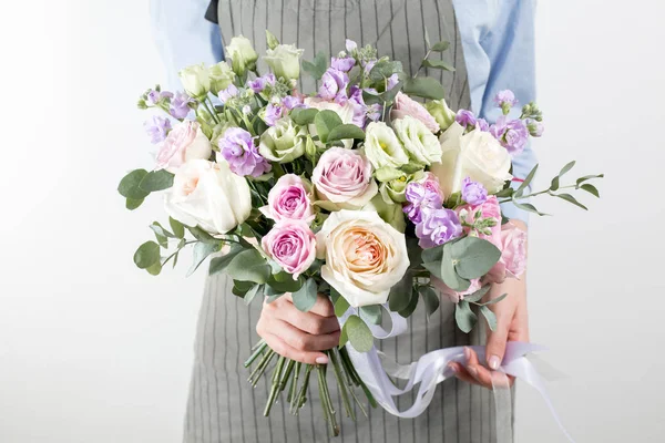 Mooi boeket gemaakt van verschillende bloemen in de hand van het jonge meisje. kleurrijke kleur mix bloem. Werkkleding in een blauw shirt en grijze schort — Stockfoto