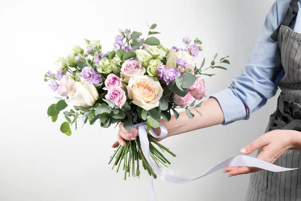 Mooi boeket gemaakt van verschillende bloemen in de hand van het jonge meisje. kleurrijke kleur mix bloem. Werkkleding in een blauw shirt en grijze schort — Stockfoto