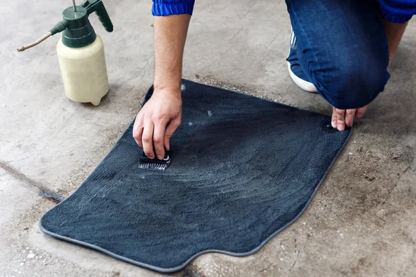 Détails du nettoyage automobile - mâle utilisant des solutions chimiques professionnelles pour nettoyer les tapis de sol de voiture — Photo