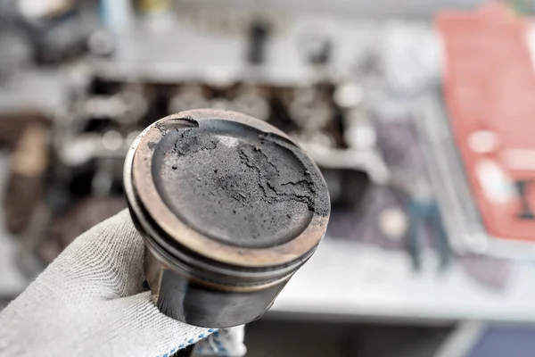 Mecánico reparador en los trabajos de reparación de mantenimiento de motores de automóviles. mantener en la mano el pistón con depósitos de carbono — Foto de Stock