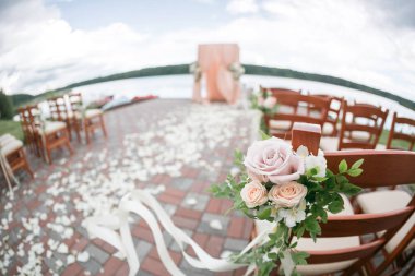 Düğün kemer çiçek ve Orman Gölü arka plan üzerinde ahşap sandalye ile dekore edilmiş.