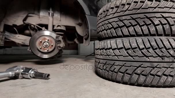 Pistola de ar para apertar um pneu parafusos em um carro suspenso em uma loja de automóveis — Vídeo de Stock