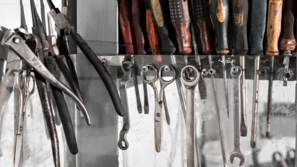 Assortiment de le faire vous-même des outils de travail suspendus dans un placard contre un mur. huile moteur sale — Video