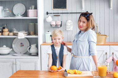 Anne oğluna meyve keser. dilimlenmiş portakal ahşap kesme tahtası üzerinde. Sağlıklı ve lezzetli kahvaltı
