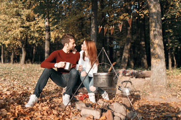 autumn camping. happy couple hugging and making tea or coffee. warm drinks.