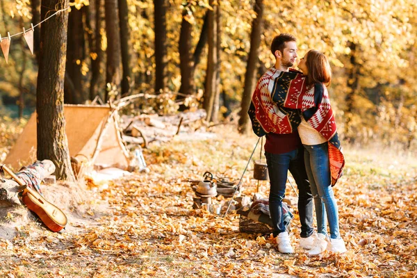 autumn camping. happy couple hugging and two under one warm blanket