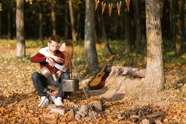 autumn camping. happy couple hugging and two under one warm blanket