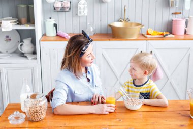 Anne ve oğul mutfakta bir kahvaltı yaparken gülümsüyorsun. Birbirinize bakın