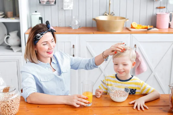 Anne Çocuk kafasına pats. oğlu ve genç anne mutfakta Kahvaltı.
