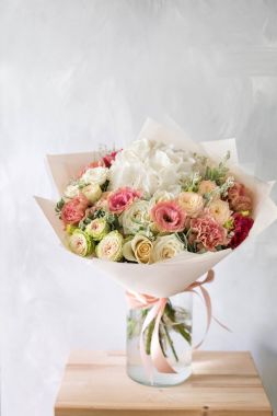 Gül ve karışık çiçek hafif bir arka plan üzerinde cam vazoda çiçek kompozisyon.