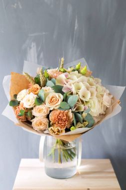 Gül ve gri arka plan üzerinde cam vazoda karışık çiçek çiçek kompozisyon.