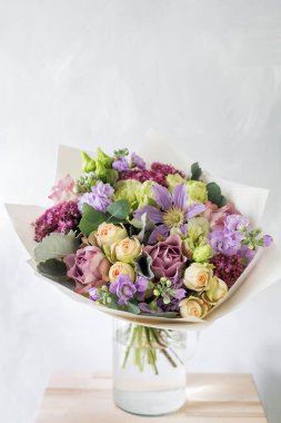 Gül ve karışık çiçek hafif bir arka plan üzerinde cam vazoda çiçek kompozisyon.