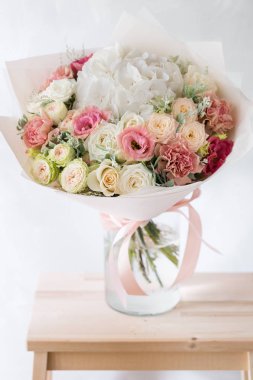 Gül ve gri arka plan üzerinde cam vazoda karışık çiçek çiçek kompozisyon.