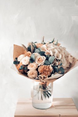 Gül ve gri arka plan üzerinde cam vazoda karışık çiçek çiçek kompozisyon.