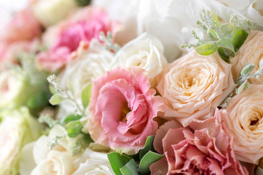 Close-up floral composition with roses and mix flowers on a light background.