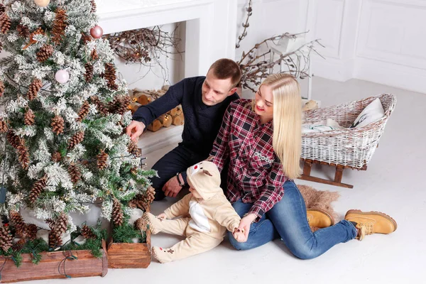 Šťastná rodina o Vánocích. Rodiče a dítě sedí na podlaze a usmívá se. — Stock fotografie