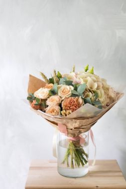 Gül ve gri arka plan üzerinde cam vazoda karışık çiçek çiçek kompozisyon.