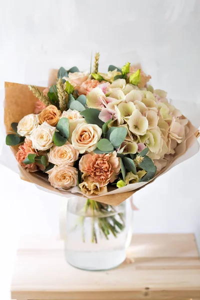 Floral composition with roses and mix flowers in glass vase on a gray background. — Stock Photo, Image