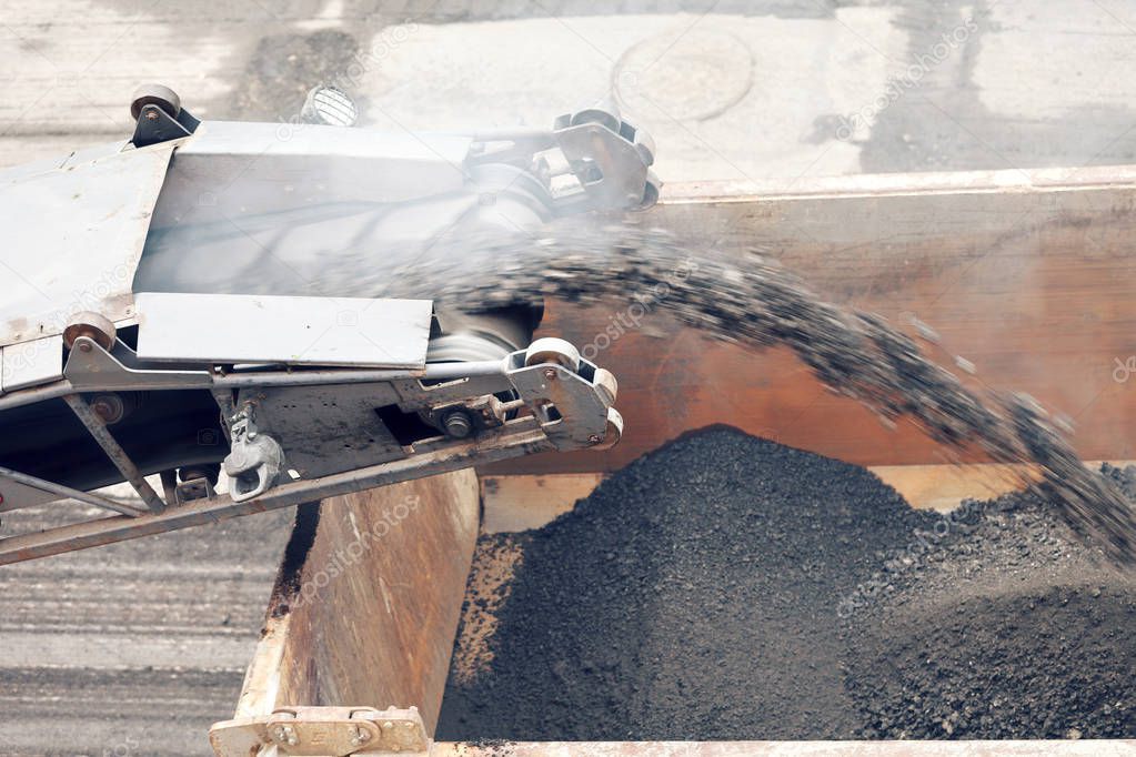 Road works. Asphalt removing machine loading powdered asphalt on the truck