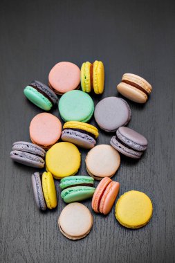 Renkli Fransızca macaroons veya macarons siyah ahşap masa üzerinde. Metin için yer.