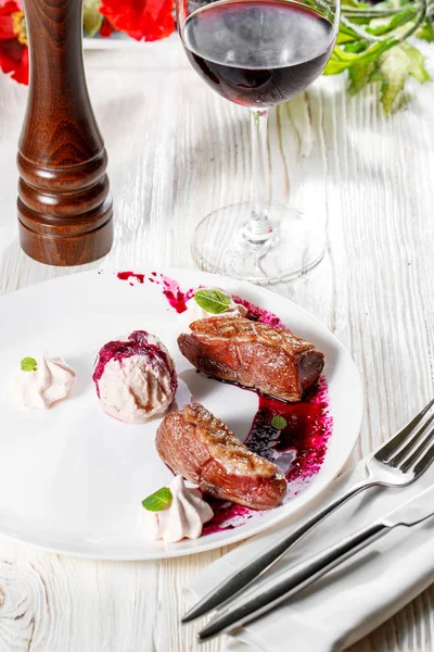 Beyaz tabakta kiraz nar soslu ördek göğsü. ahşap arka plan.