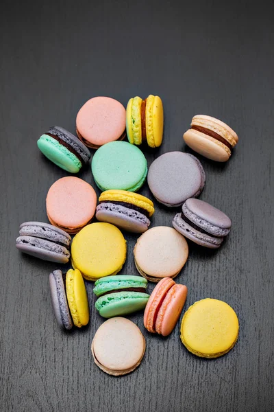 Renkli Fransızca macaroons veya macarons siyah ahşap masa üzerinde. Metin için yer.