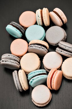 Renkli Fransızca macaroons veya macarons siyah ahşap masa üzerinde. Metin için yer.
