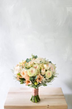 Gül ve gri arka plan üzerinde cam vazoda karışık çiçek çiçek kompozisyon.