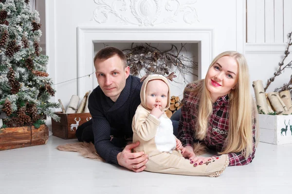 Šťastná rodina o Vánocích. Rodiče a dítě ležící na podlaze a usmívá se. — Stock fotografie