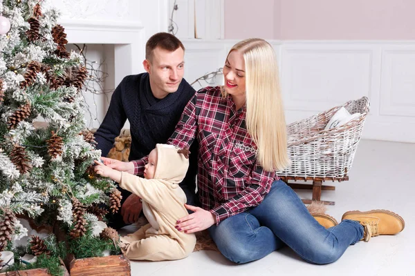 Šťastná rodina o Vánocích. Rodiče a dítě sedí na podlaze a usmívá se. — Stock fotografie