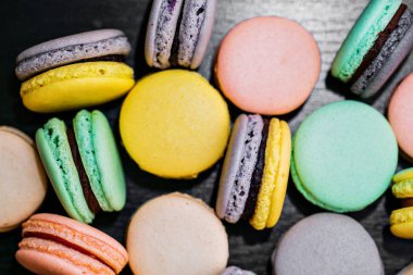 Renkli Fransızca macaroons veya macarons siyah ahşap masa üzerinde. Metin için yer.
