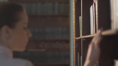 Bayan Üniversite öğrenci alarak kitap raf Kitaplığı'nda. kurşun el kitaplar raflarda