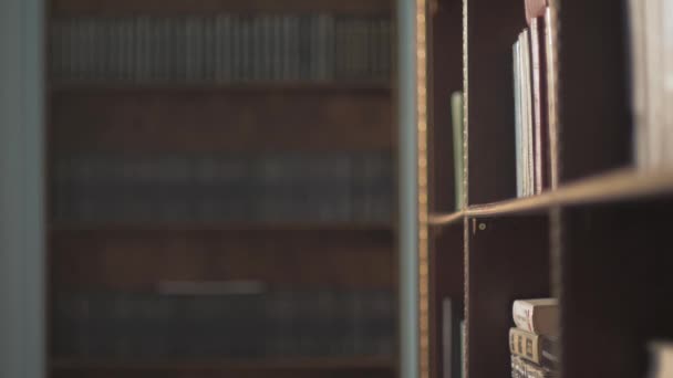 Vrouwelijke college student nemen boek van de plank in de bibliotheek. hand leiden op de planken met boeken — Stockvideo