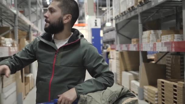 Un bell'uomo che fa shopping in un supermercato o magazzino — Video Stock