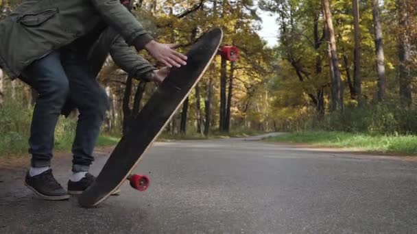 Man rijden op een longboard schaatsen op een weg door een bos — Stockvideo